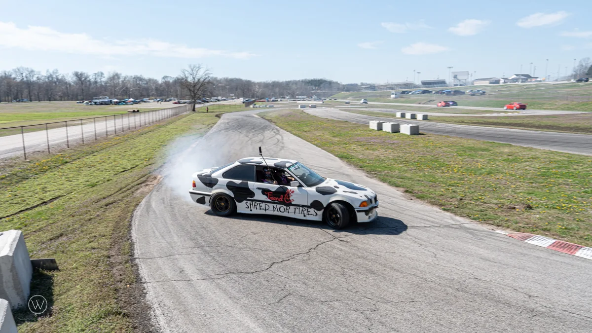Two drift cars running tandem through a track corner